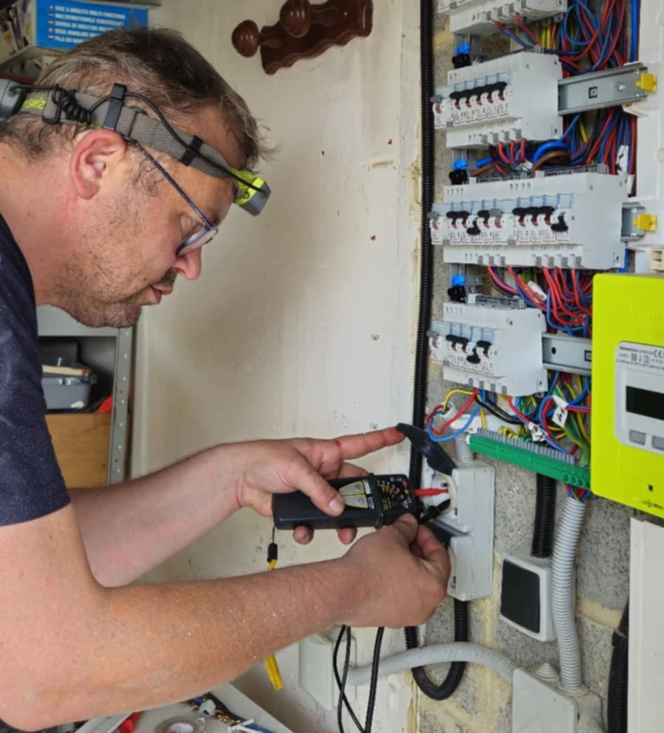 Électricien ADN ELEC contrôlant un tableau électrique avec un appareil de mesure