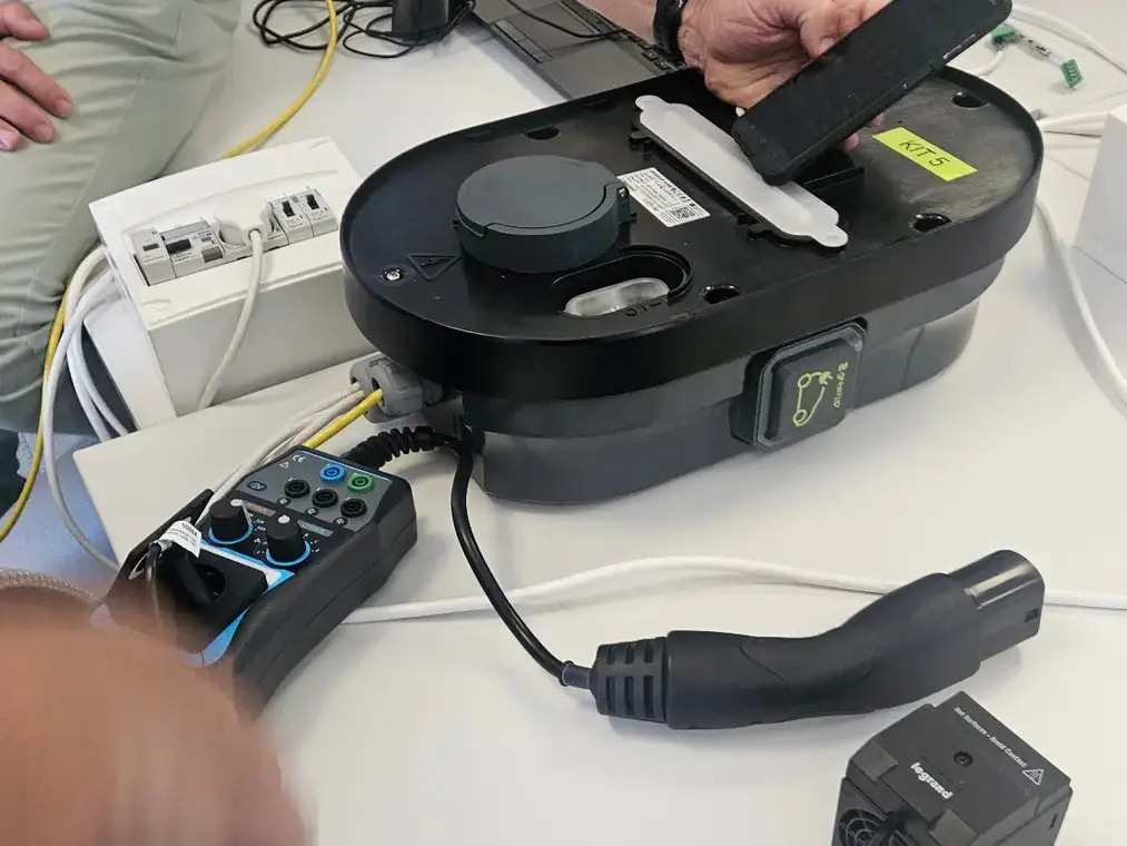 Matériel de contrôle et composants d’une borne de recharge examinés sur une table de travail